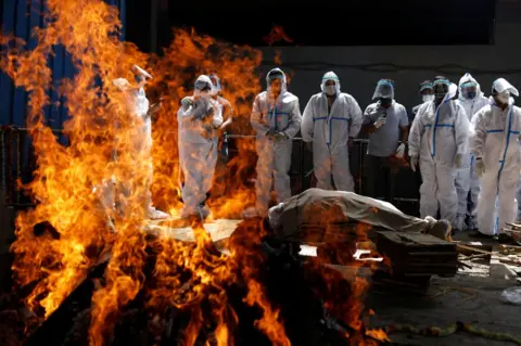 Adnan Abidi / Reuters Relatives attend the cremation of a Covid victim in New Delhi, India