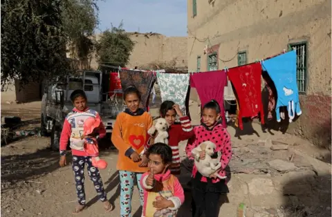 Getty Images Girl giving a thumbs up next to a clothing lines. There are four other girls behind her.