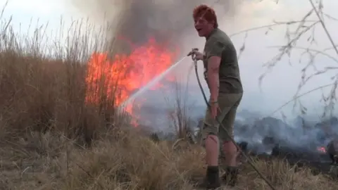 Bernadette Hall puting out a bush fire in South Africa