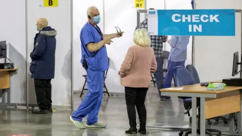 Paul Faith/AFP Health staff member in discussion at the SSE Arena in Belfast