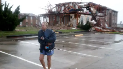 Getty Images A woman walks away from a destroyed apartment building