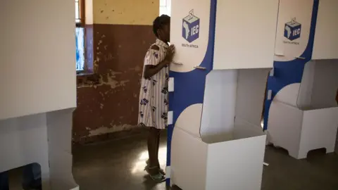 Getty Images A girl watches while her mother marks her ballot at at a polling station at the Sheshego township, on the outskirts of Polokwane on May 8, 2019.