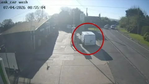 White van parked on petrol forecourt next to fuel pump 