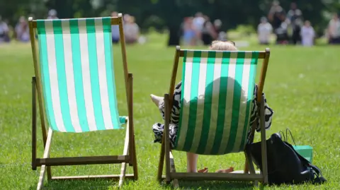 PA Media Two deck chairs sitting in a park in sunny weather