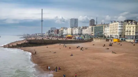 A view over Brighton seafront. There is a pebbled beach and buildings in the background. 