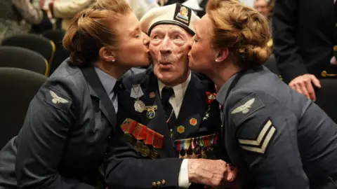 PA Media D-Day veteran Alec Penstone receives a kiss from the 'D-Day Darlings' at a D-Day event in 2024