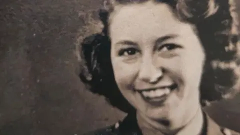 Head and shoulders image of a smiling 20 year old woman with curled hair taken in 1943