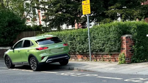 Middlesbrough Council Green car parked over road markings saying 'school keep clear'