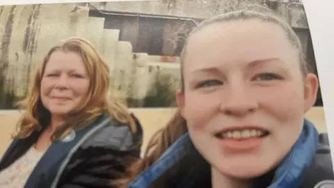 Teresa Hall A selfie shows Teresa and Morgan both smiling and looking at the camera. Morgan is wearing a denim jacket and has a ponytail. Teresa has red shoulder-length hair.