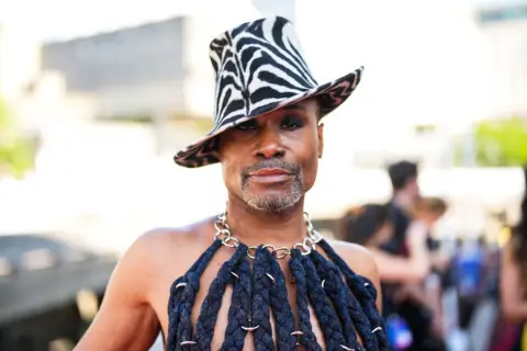 Getty Images Billy Porter poses on a red carpet wearing a zebra skin hat and a corset made of ropes and chains