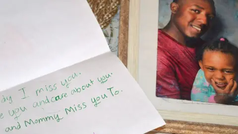 Anselm Gibbs Fragment of Amarah's letter to her slain father Shakeem Charles beside a photo of the two of them together