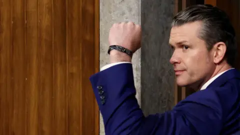 Reuters Pete Hegseth holds his fist in the air as he glances to his left.