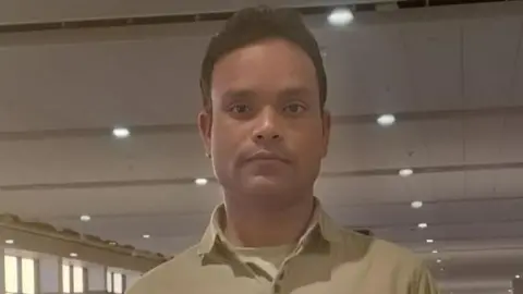 Mohammad Sartaj Alam/BBC Masood Alam, one of the crew members, wearing a tee shirt, poses before the camera in the premises of an airport.
