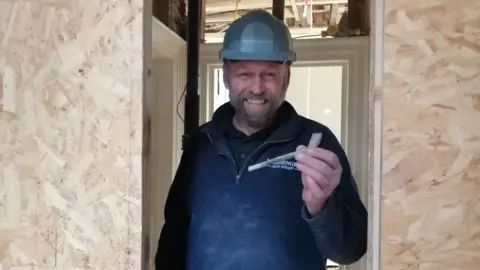 HB Archaeology & Conservation Limited A man with a hard hat is holding an old tobacco pipe in a construction site