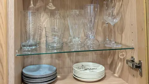 St Michael's Hospice Plates and glasses are stacked in a cupboard.