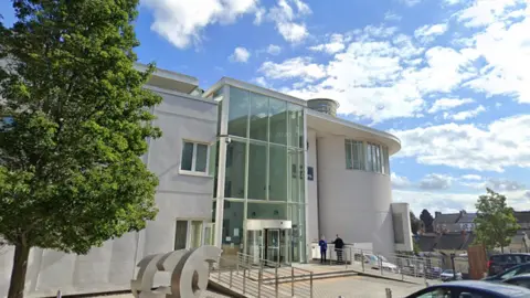 A large light-coloured building with a large glass entrance hall.