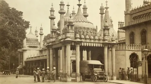 A black and white archive image shows the Royal Pavilion in Brighton with domes and minarets, with a military vehicle and people outside during World War One.