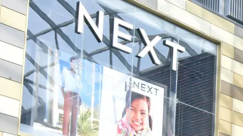 Next plc Side of a Next shop building featuring posters and the retailer's logo