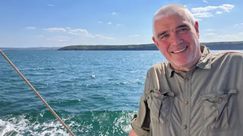 Magnus Johnson A man with grey hair smiling on a boat on the sea