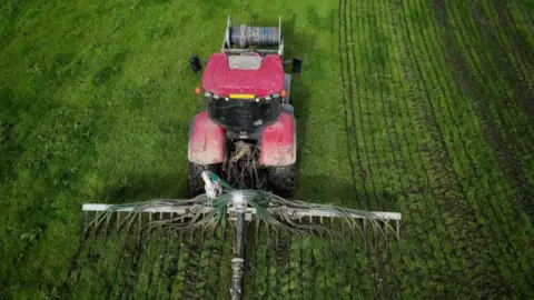 A tractor spreading slurry in a field 