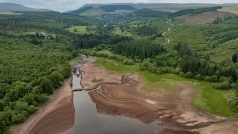 Getty Images Aerial drone view looking down on the bridge and a wider dry expanse of the bed of the reservoir, surrounded by trees