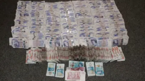CPS handout multiple piles of British cash on a carpet
