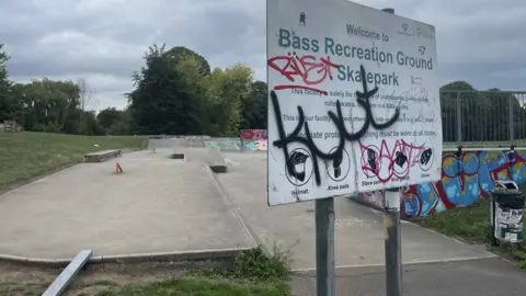 A skate park sat behind a graffitied sign