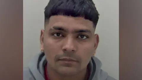 A close-up portrait shows Jaskirat Singh facing the camera against a plain light background, with short dark hair, a grey hooded top and small earrings visible.