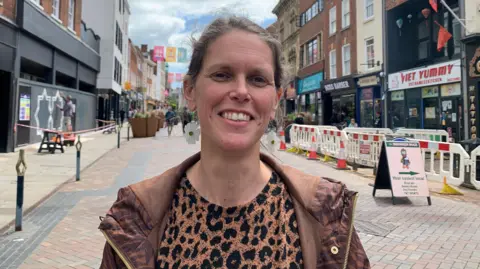A photo showing Emily Gibbon from Gloucester BID standing in a street in Gloucester with shop fronts either side
