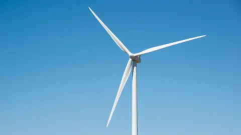 A lone wind turbine against a blue sky