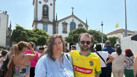 Sofia Ferreira Santos/BBC Rafaela and Fábio standing next to each other in front of a white church