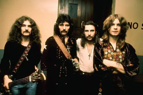 Getty Images Four band members, two with guitars, and all with long hair