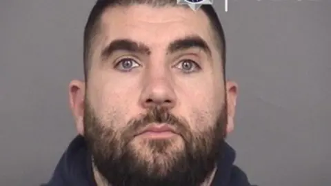 Jose Ivo Ferreira mugshot. He has brown hair, a brown beard and blue eyes.