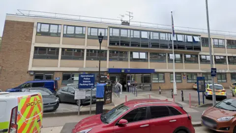 Google The exterior of Basildon police station. A modern, three-storey brick building with cars parked outside.