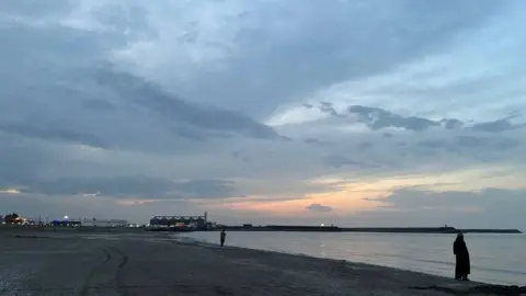 A woman stands on a Caspian Sea beach in Iran