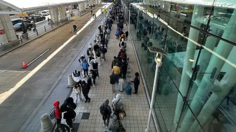 People in a line outside the airport