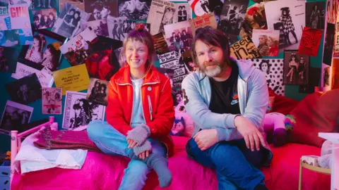 Euan Robertson Since Yesterday's co-directors Carla J Easton and Blair Young, sitting on a bed surrounded by pictures and posters of girl bands.