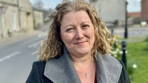 Faye Purbrick looking at the camera in a village