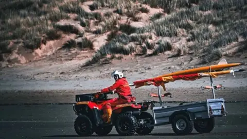 Richard Plimley RNLI lifeguard on vehicle