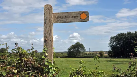 BBC A public footpath sign with greenery in the background