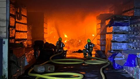 Firefighters tackle the fire which is seen burning inside a building