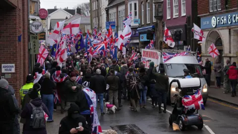 PA Media People holding Union Jack flags and St George's Cross flags take part in a protest in Crowborough high street.