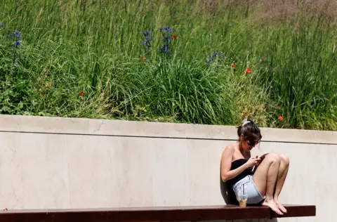 EPA A person enjoys the sunshine and warm weather at United States Embassy Park in London