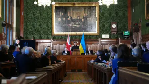 Reuters Nato Secretary General Mark Rutte, Lord McFall, Lord Speaker of the UK House of Lords, Speaker of the House of Commons Sir Lindsay Hoyle and Prime Minister Sir Keir Starmer listen as Ukrainian President Volodymyr Zelensky (centre) delivers a speech to Members of Parliament, in Committee Room 14 at the House of Commons