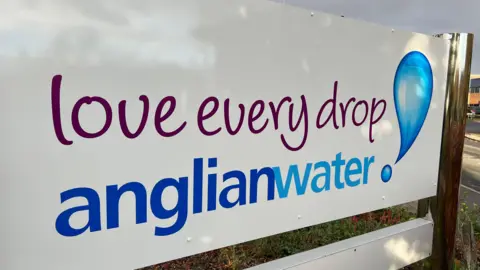 A sign for Anglian Water that reads "Love every drop" with an image of a blue water droplet. 