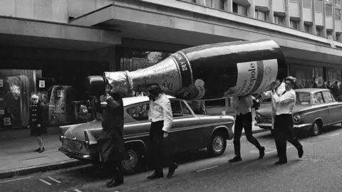 Getty Images A giant champagne bottle outside the department store Rackhams, Birmingham, West Midlands, 3rd November 1966. 