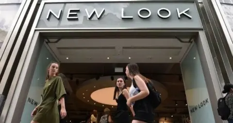 New Look store with three female shoppers walking past entrance 