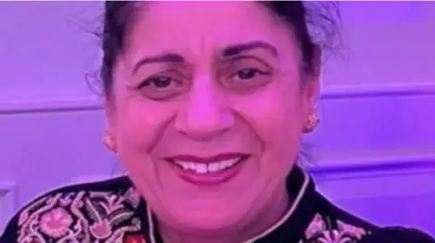 A picture of Pulvinder Dhillon, who has long hair tied back and is wearing gold earrings. She is smiling for the camera.