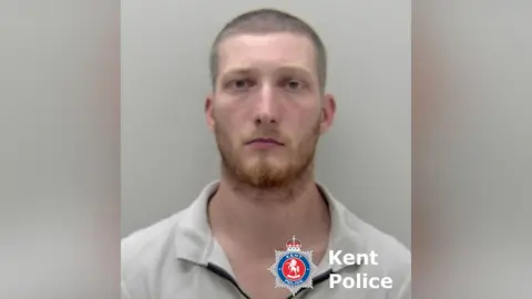 A man with a stern expression in a police mugshot.