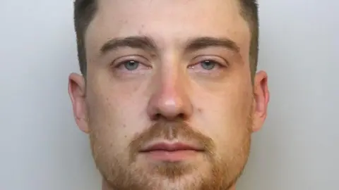 Avon and Somerset Police A man is looking at a camera in a police mugshot with red, bleary eyes